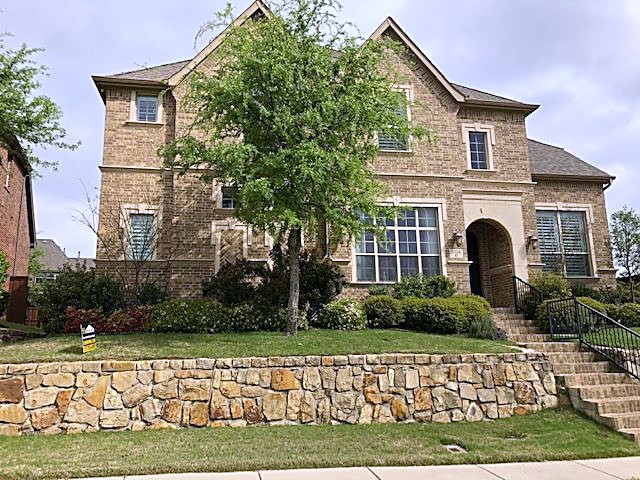 A two-story brick home with a finished asphalt shingle roof