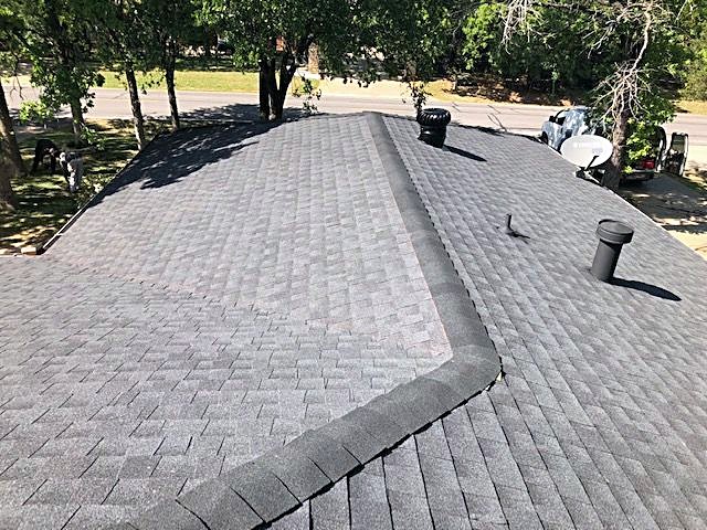 A finished gray shingle roof seen from the ridge
