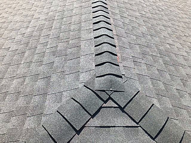 Ridge cap shingles running down a newly finished roof
