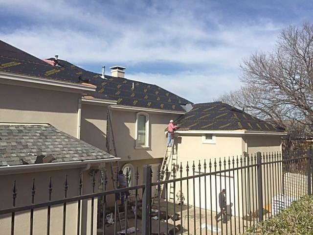 Crew at work on the roof of a stucco home