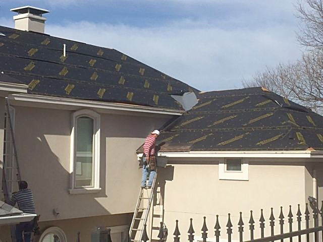 A roofer working at the eave of a stucco home